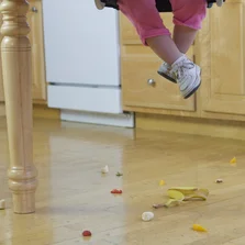 Langlebig und strapazierfähig - Low section view of a baby girl with spilled food on the floor - Stock-Fotografie