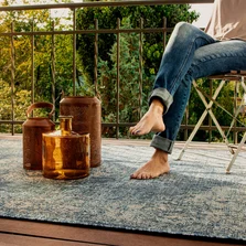 Eine Frau sitzt auf einem Stuhl, barfuß auf einem Outdoor Teppich. - Eine Frau sitzt auf einem Stuhl, barfuß auf einem Outdoor Teppich.