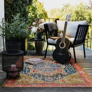 Illustration - Ihr Experte für schönes Wohnen - Ein bunt gemusterter Orient Vintage Outdoor Teppich liegt auf einem Balkon
